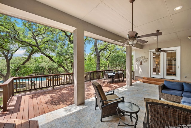wooden deck with an outdoor hangout area, a fenced in pool, a patio area, outdoor dining area, and a ceiling fan