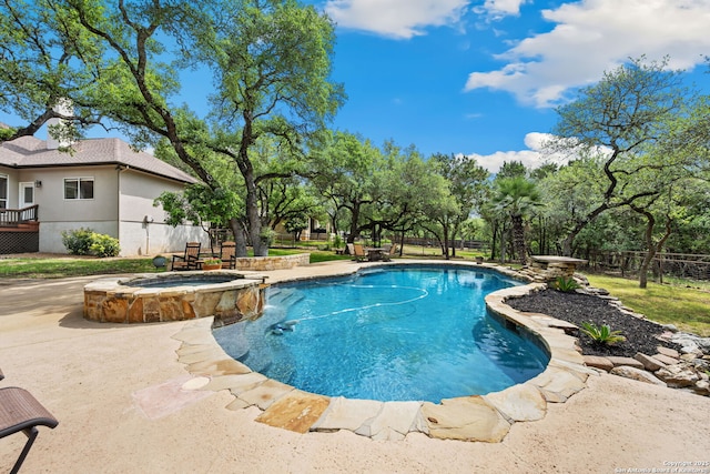 view of pool with fence, a patio, and a pool with connected hot tub