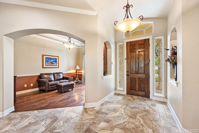 foyer featuring stone tile floors, baseboards, and arched walkways