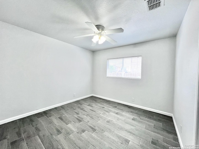 spare room with baseboards, visible vents, wood finished floors, and a ceiling fan
