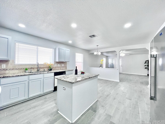 kitchen featuring light stone countertops, a sink, visible vents, wood finish floors, and dishwasher