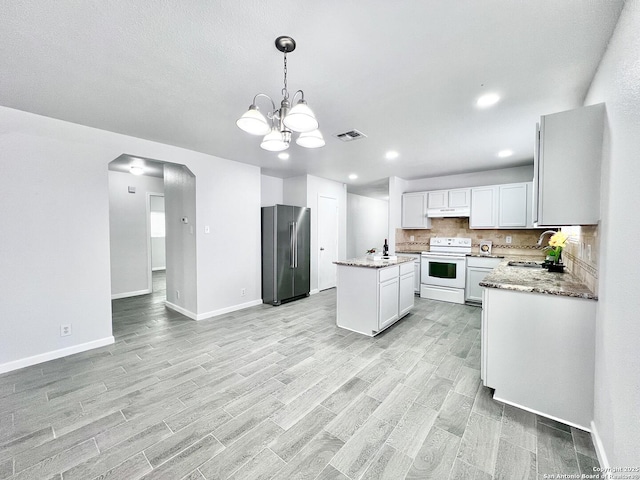 kitchen with under cabinet range hood, high end refrigerator, a sink, visible vents, and white electric range