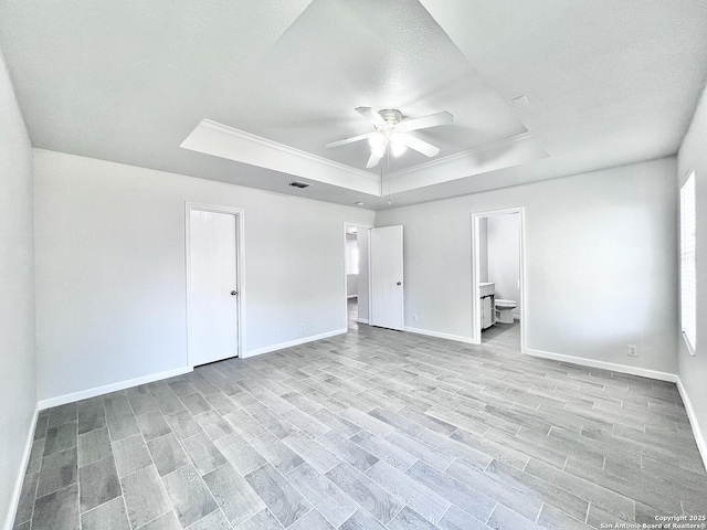 unfurnished bedroom with wood finished floors, baseboards, visible vents, a raised ceiling, and crown molding