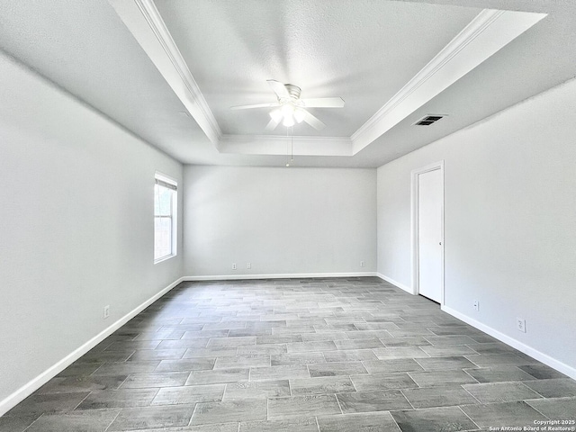 unfurnished room featuring ornamental molding, ceiling fan, baseboards, visible vents, and a raised ceiling