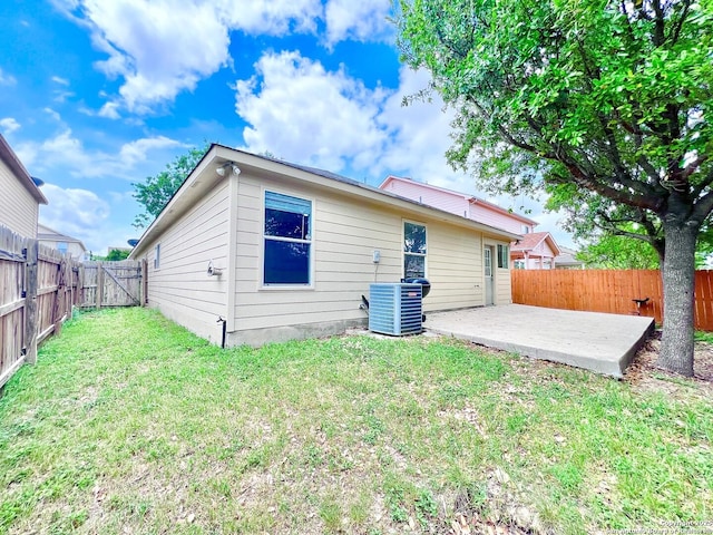 rear view of house with cooling unit, a yard, a patio, and a fenced backyard