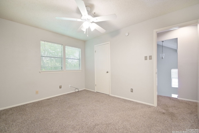 carpeted empty room with a ceiling fan, a textured ceiling, and baseboards