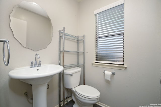 half bath with a sink, toilet, and baseboards