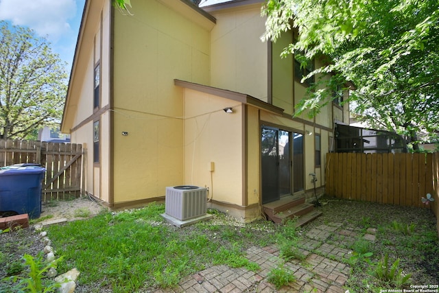 rear view of property with fence, entry steps, and stucco siding