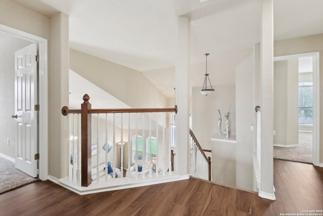 hallway with an upstairs landing, wood finished floors, and baseboards