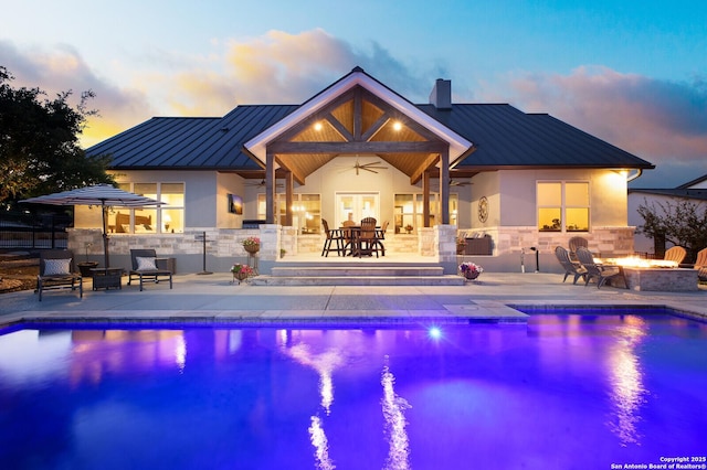 pool at dusk featuring a patio, a fire pit, ceiling fan, and a fenced in pool