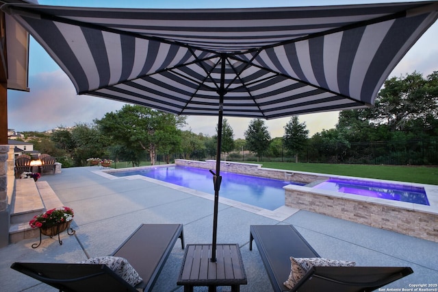 pool at dusk featuring fence, an outdoor pool, a patio area, and an in ground hot tub
