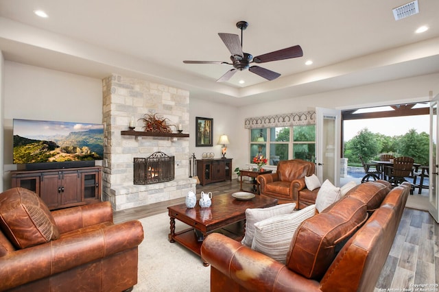 living area with visible vents, a tray ceiling, recessed lighting, wood finished floors, and a ceiling fan
