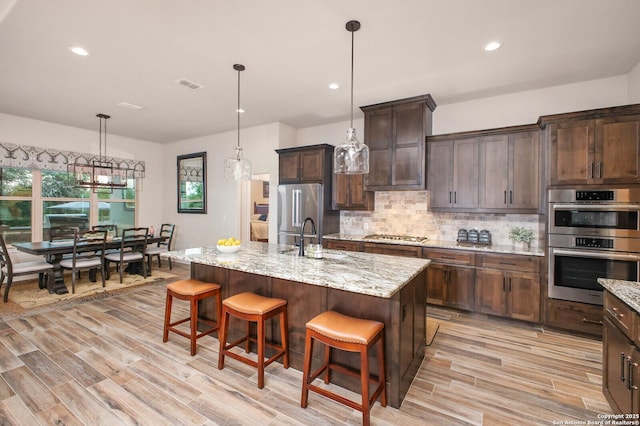 kitchen featuring visible vents, appliances with stainless steel finishes, light wood finished floors, and a sink