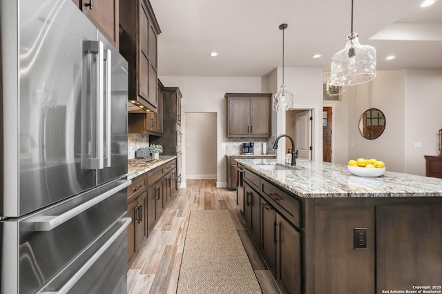 kitchen featuring tasteful backsplash, an island with sink, recessed lighting, light wood-style floors, and appliances with stainless steel finishes