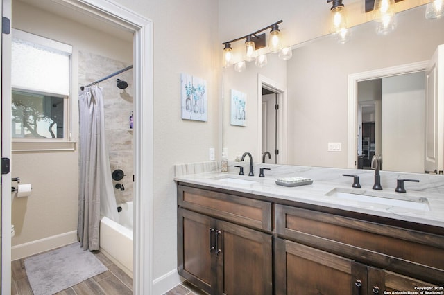 bathroom with baseboards, shower / tub combo with curtain, double vanity, and a sink