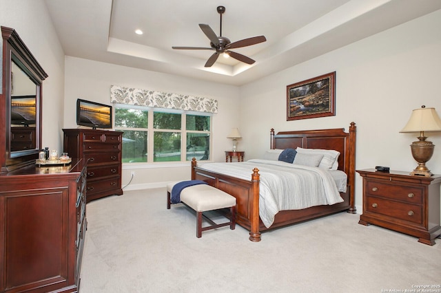 bedroom with recessed lighting, ceiling fan, a tray ceiling, baseboards, and light colored carpet