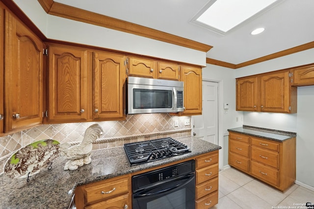 kitchen featuring dark stone counters, black appliances, brown cabinetry, and tasteful backsplash