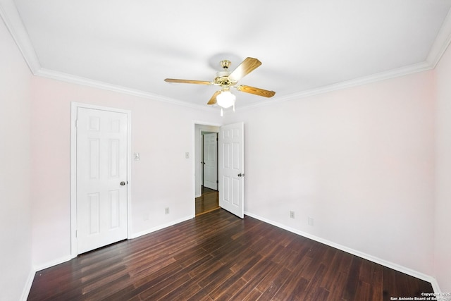 empty room with dark wood finished floors, baseboards, ornamental molding, and a ceiling fan