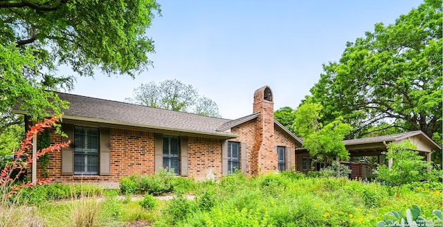 rear view of house with a chimney and brick siding