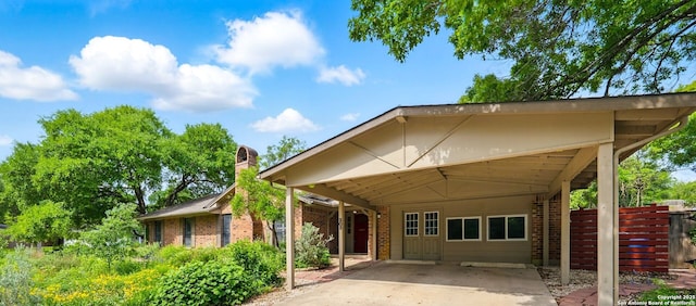 view of front of house with concrete driveway, fence, an attached carport, and brick siding
