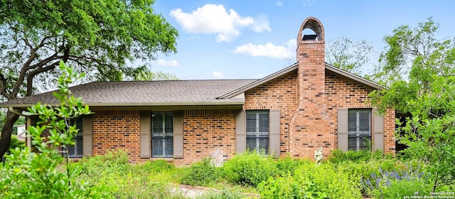 view of front facade with a chimney and brick siding
