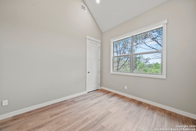 unfurnished room with baseboards, visible vents, light wood-type flooring, and lofted ceiling