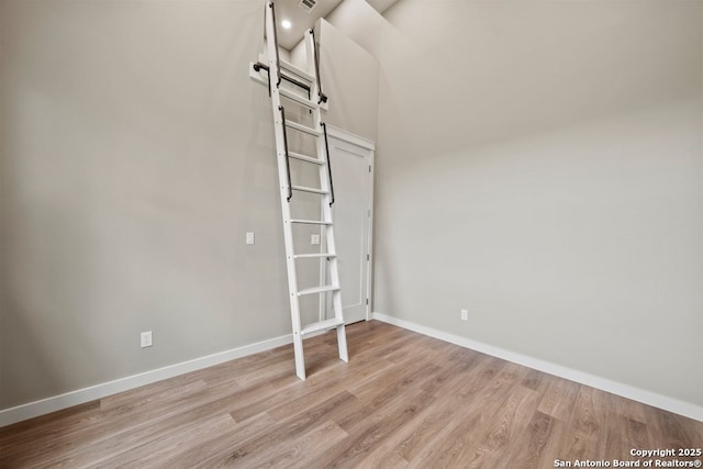 empty room featuring baseboards, a barn door, and light wood finished floors