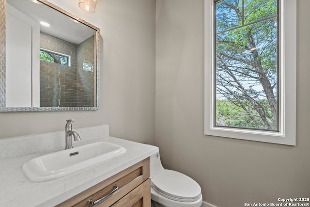 full bathroom featuring toilet, tiled shower, and vanity