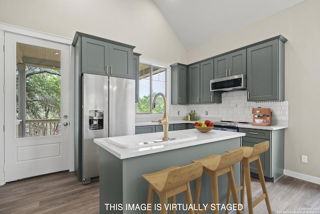 kitchen with dark wood finished floors, decorative backsplash, stainless steel appliances, light countertops, and lofted ceiling