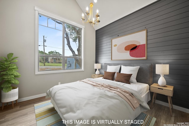 bedroom with wooden walls, wood finished floors, a notable chandelier, and baseboards