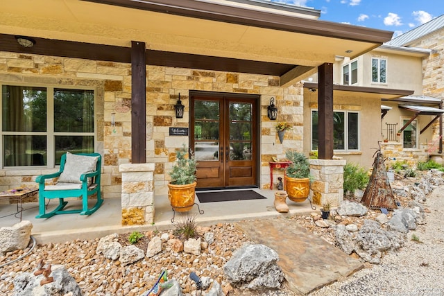 doorway to property with stone siding, stucco siding, and french doors