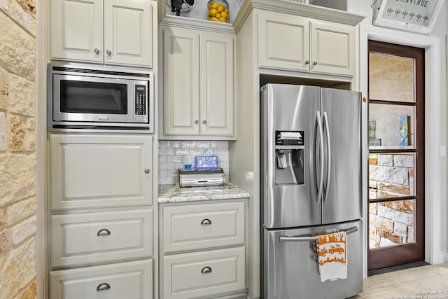 kitchen featuring light stone countertops, stainless steel appliances, white cabinets, and light tile patterned floors