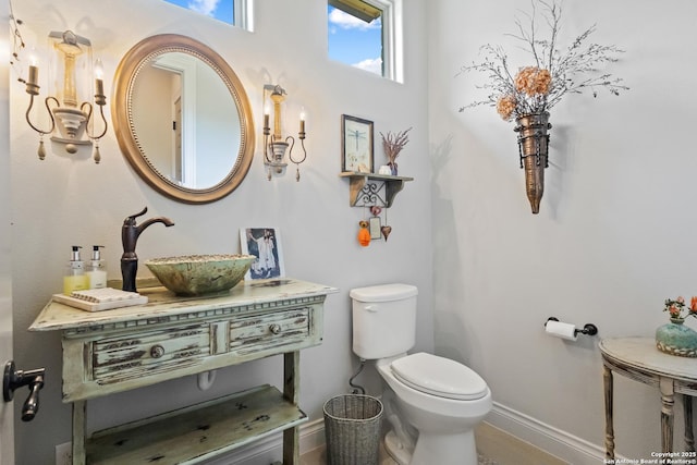 half bath featuring toilet, a sink, and baseboards