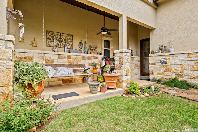 view of exterior entry featuring ceiling fan, stone siding, and stucco siding