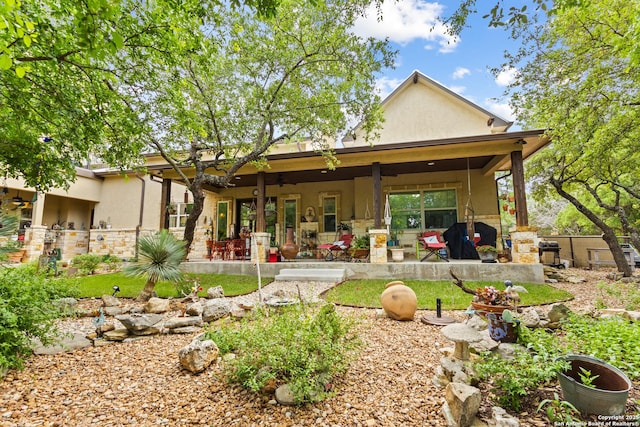 rear view of house with ceiling fan and stucco siding