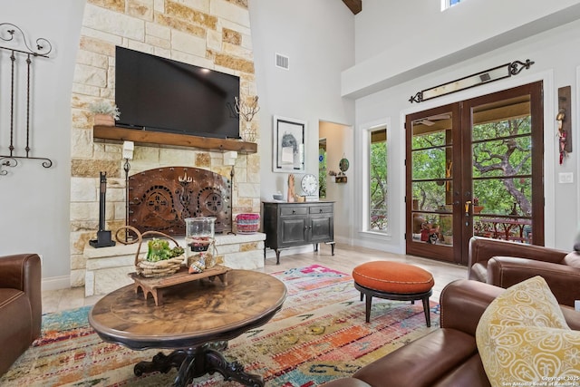 living room with a high ceiling, a fireplace, visible vents, baseboards, and french doors