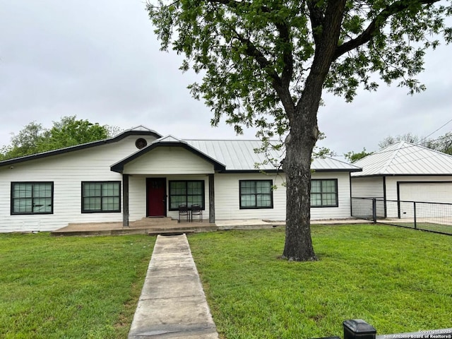 single story home featuring metal roof, a front lawn, covered porch, and fence