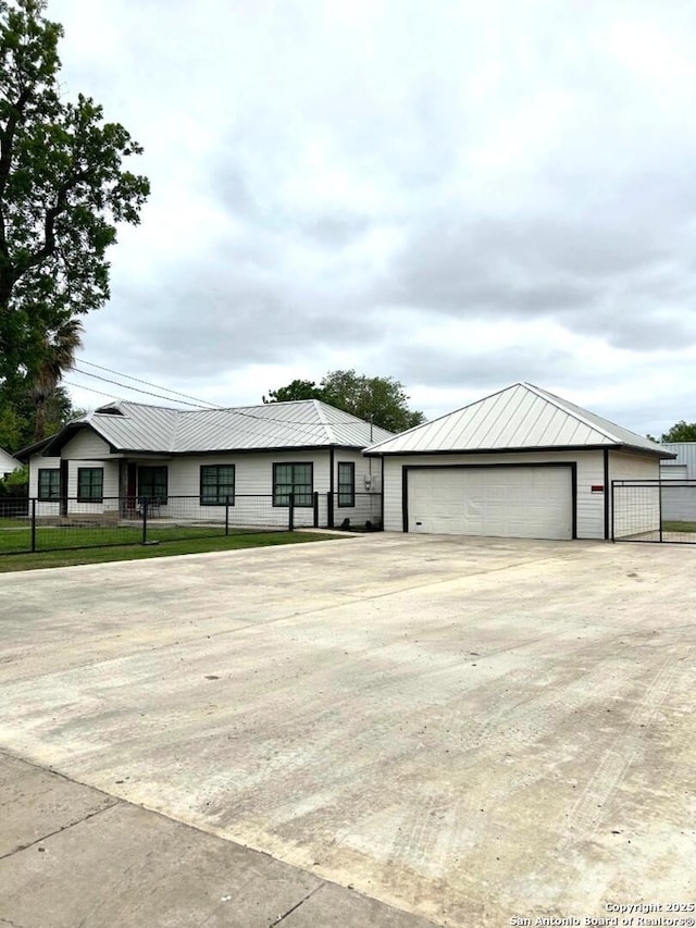 single story home with a garage, fence, an outdoor structure, and metal roof