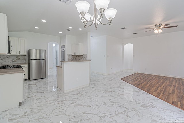 kitchen with appliances with stainless steel finishes, arched walkways, open floor plan, recessed lighting, and ceiling fan with notable chandelier