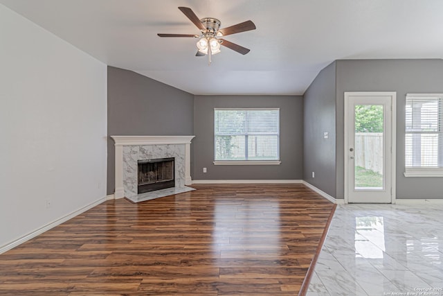 unfurnished living room featuring baseboards, a wealth of natural light, a high end fireplace, and ceiling fan