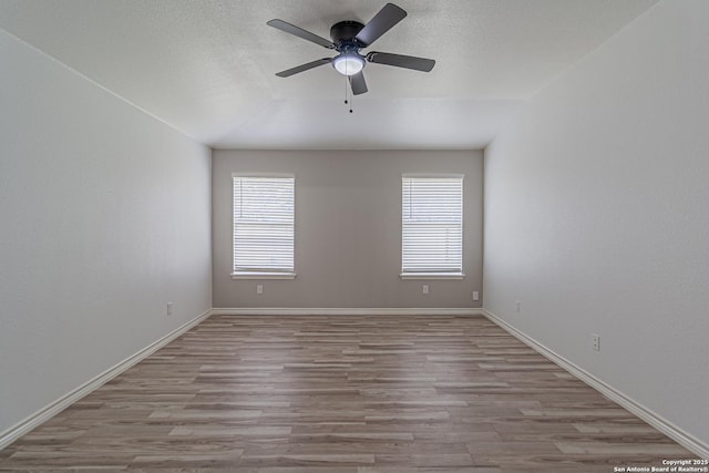 empty room with a ceiling fan, wood finished floors, and baseboards