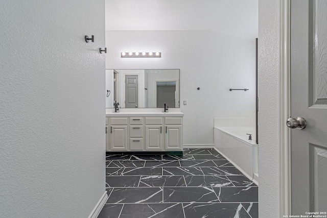 full bathroom with a garden tub, marble finish floor, a sink, and double vanity
