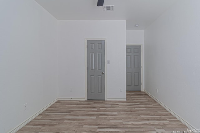 unfurnished room with visible vents, a ceiling fan, light wood finished floors, and baseboards