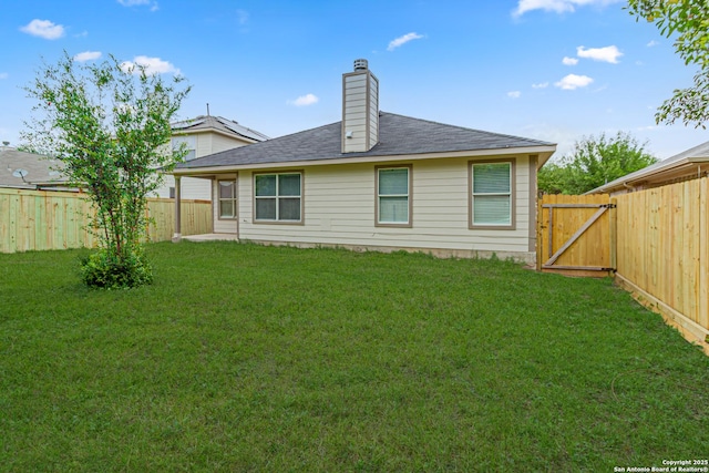 back of property with a lawn, roof with shingles, a fenced backyard, and a chimney