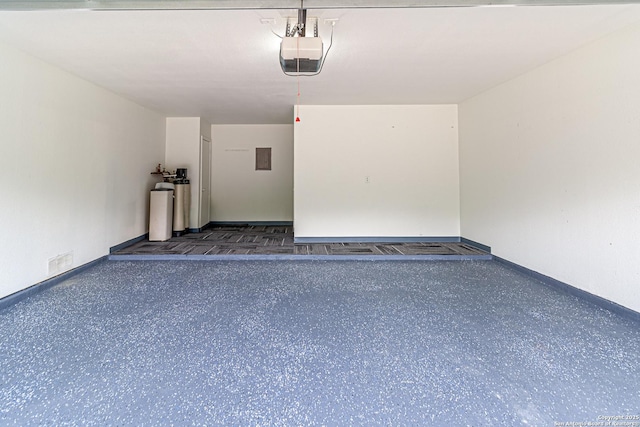 garage featuring baseboards, visible vents, a garage door opener, and electric panel