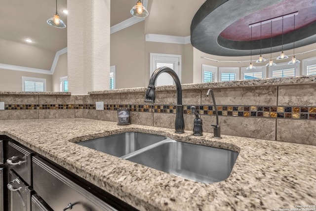 interior details with tasteful backsplash, light stone countertops, crown molding, and a sink