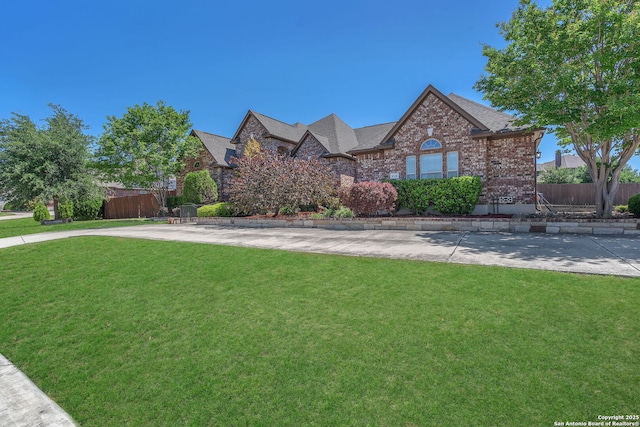 view of front of property with brick siding, fence, and a front yard