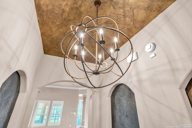 interior details with a notable chandelier, ornamental molding, and arched walkways