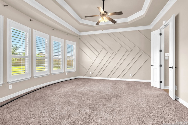 empty room featuring carpet, a raised ceiling, crown molding, and a ceiling fan