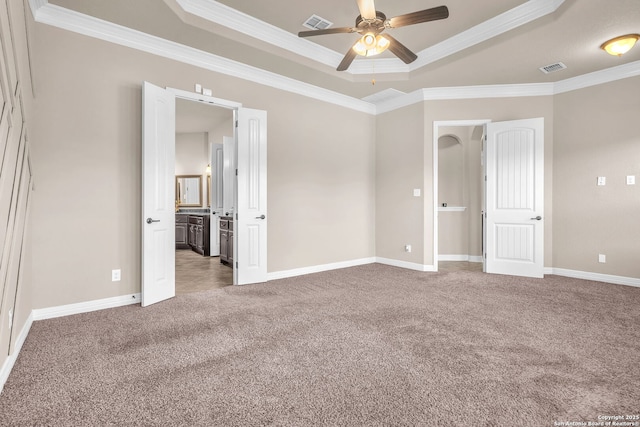 unfurnished bedroom featuring carpet, crown molding, and a tray ceiling